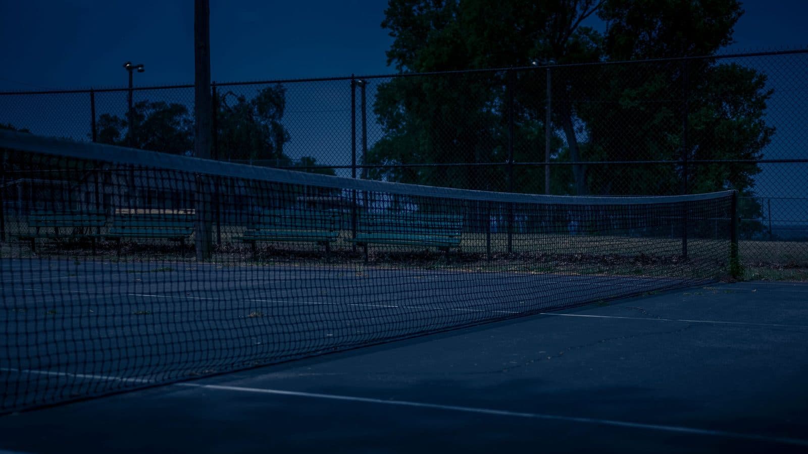 A tennis net at dusk on a London public court