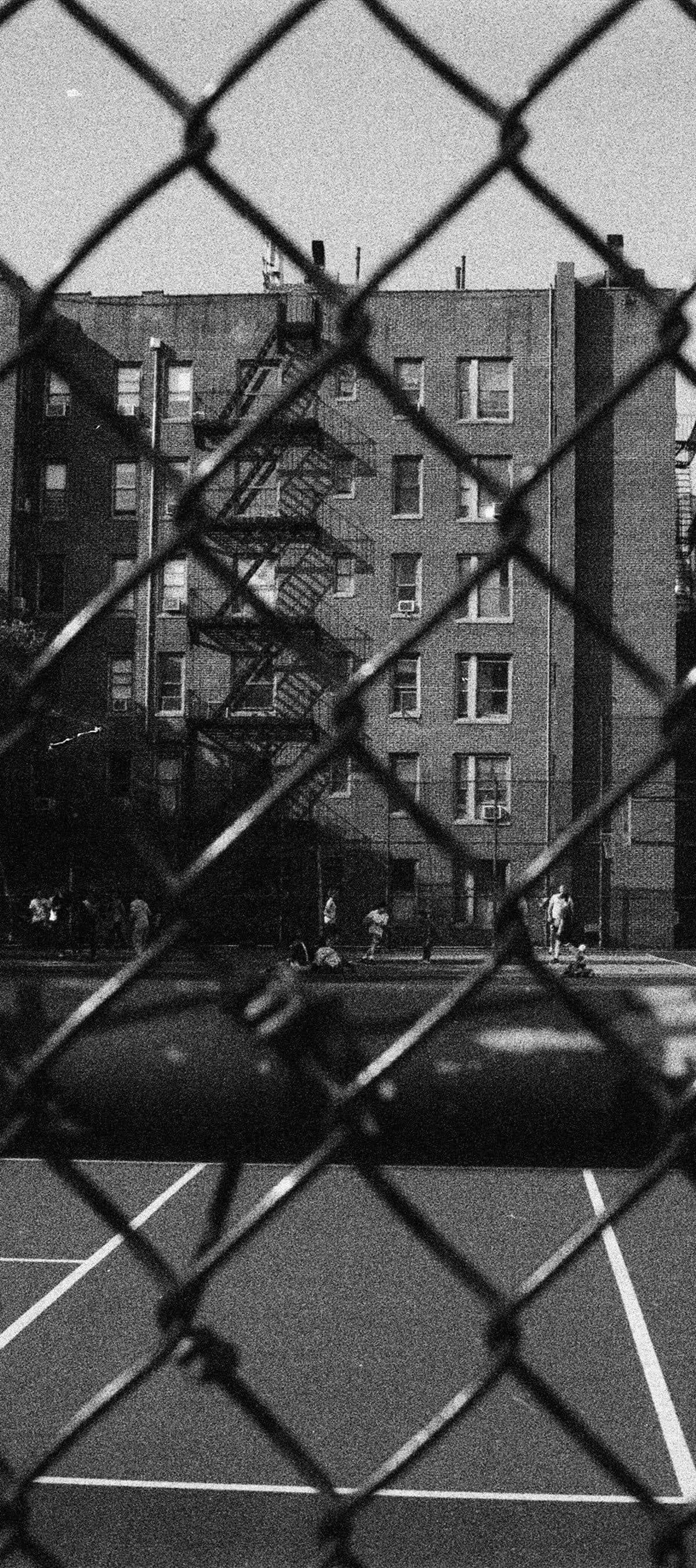 A New York public court seen through a chain-link fence, in black and white