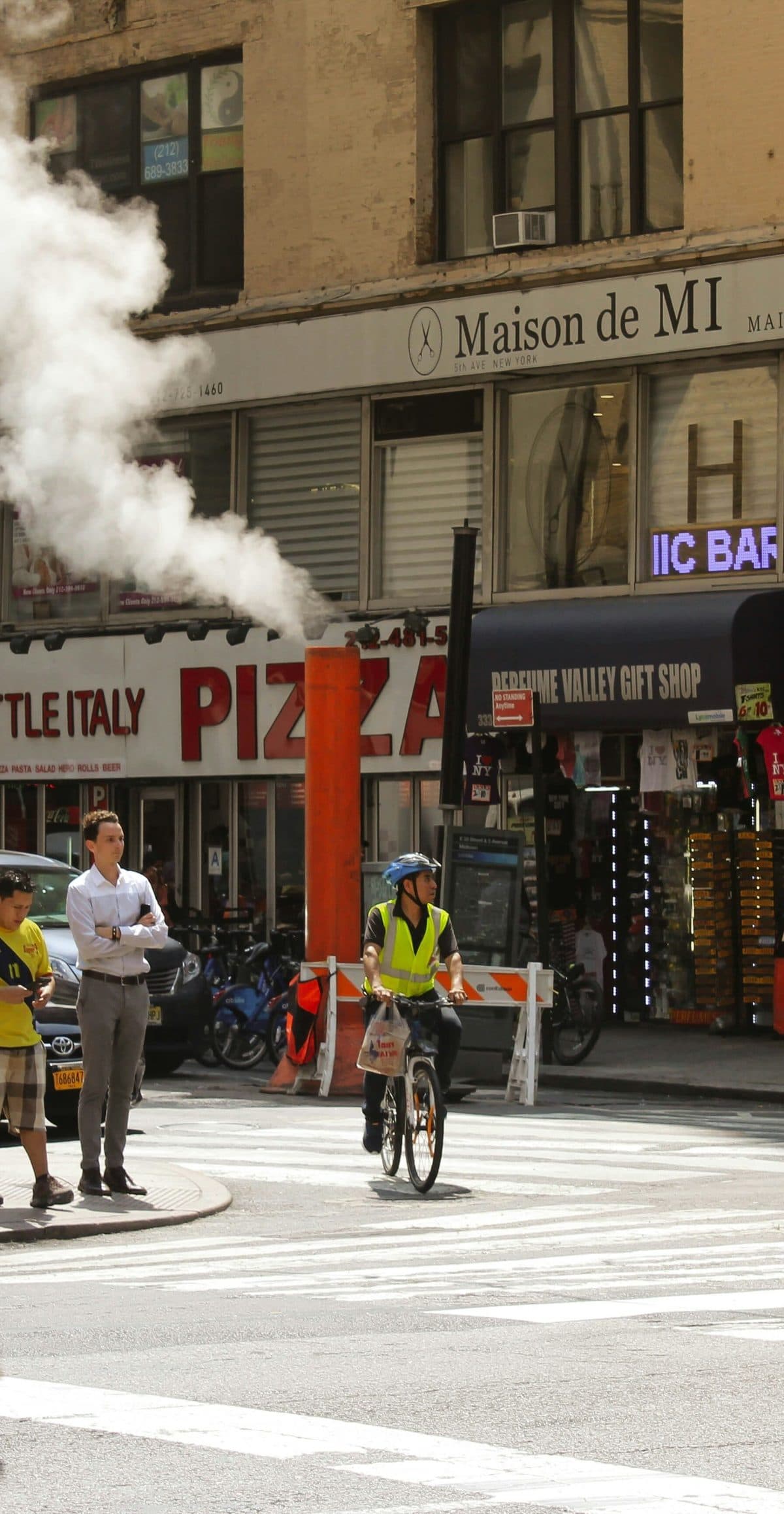 A Staten Island street corner with steam rising past shopfronts